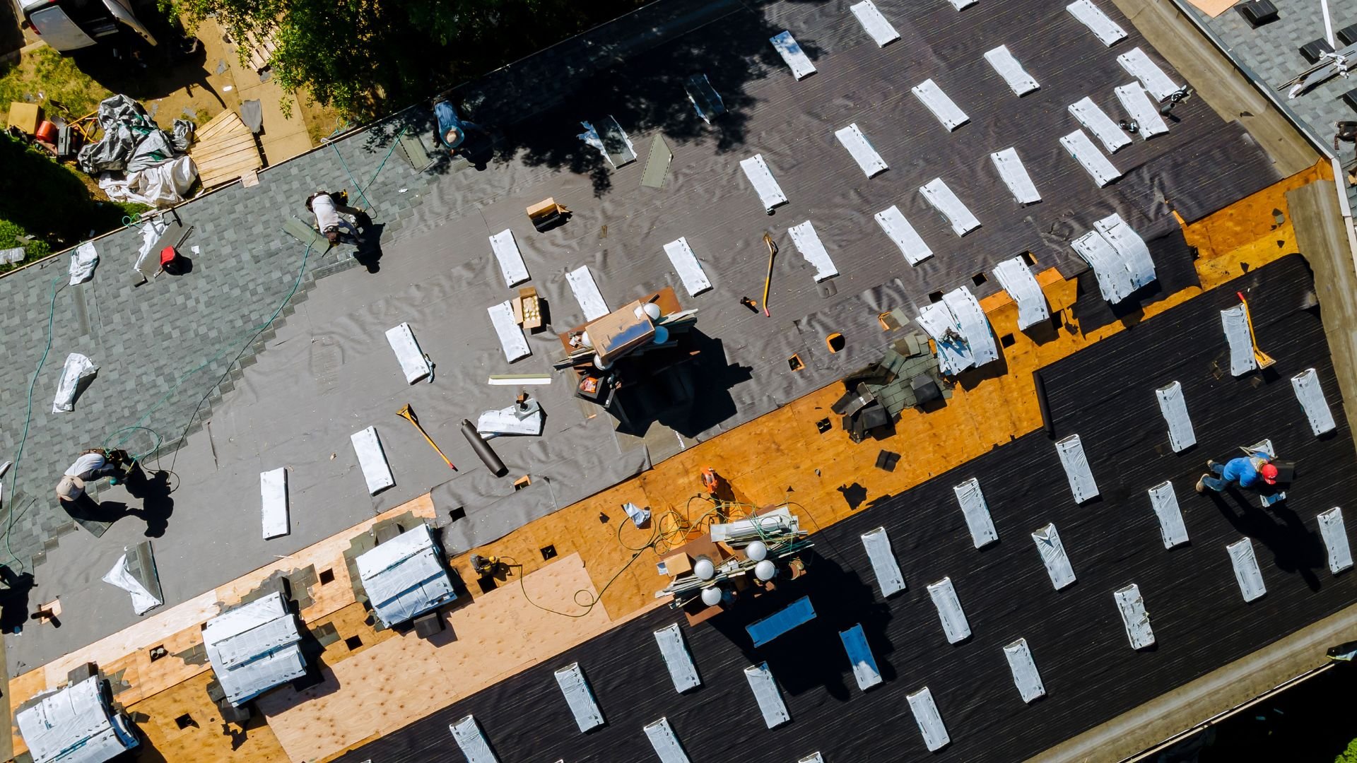 Aerial view of construction workers installing roof shingles on building