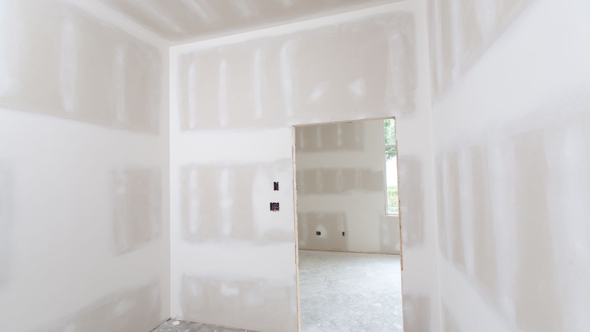 Unfinished room with drywall and an open door showing another room