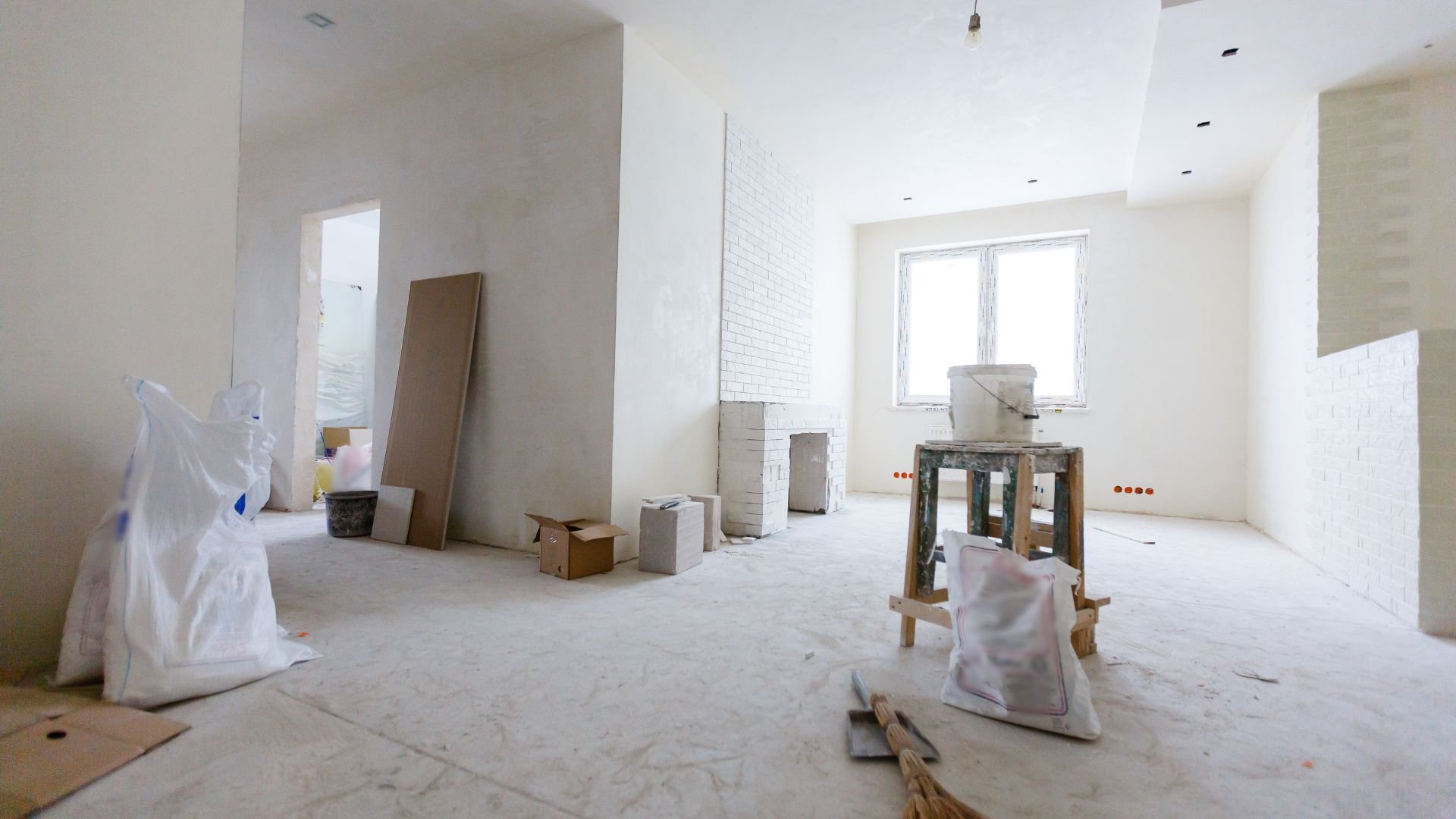 Interior room under renovation with white walls, construction materials, and tools